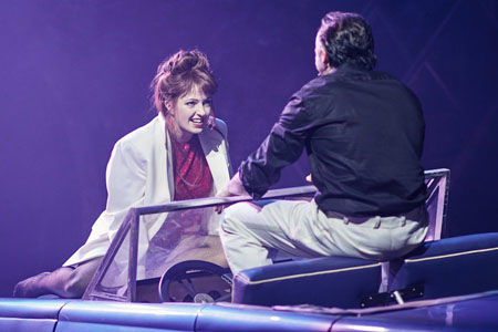Scene from Bat Out Of Hell: Sloane (Sharon Sexton) and Falco (Rob Fowler) perform Paradise By The Dashboard Light