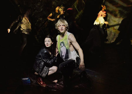 Strat (Andrew Polec) and Raven (Christina Bennington) crouch near the front of the stage