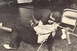 Meat Loaf lying collapsed on the floor, someone is kneeling over him and administering oxygen from a tank
